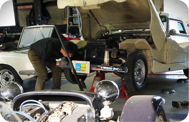 整備士がエンジンルームを点検するクラシックカーの修理風景
